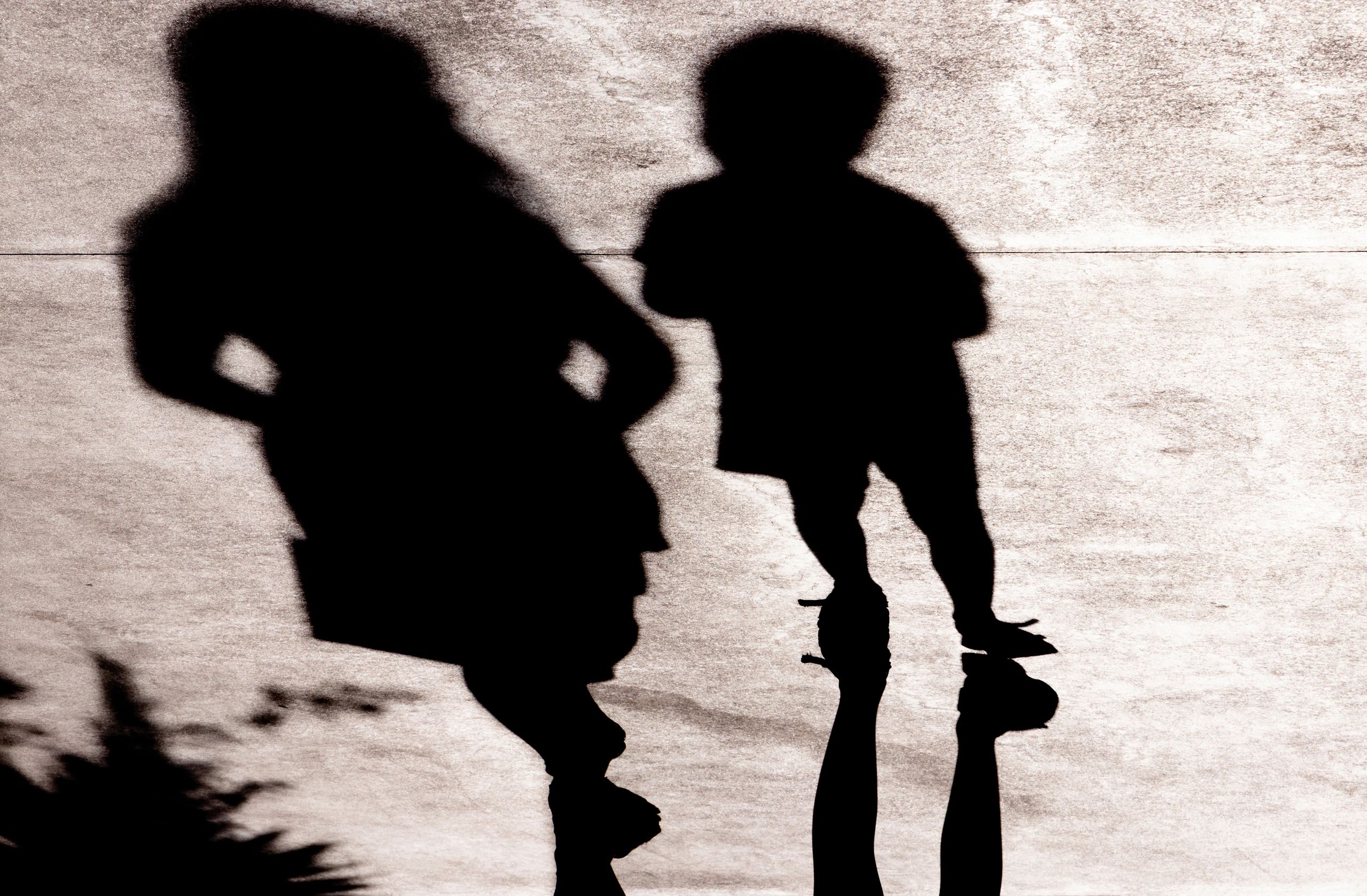 Shadow silhouettes of mother and son walking in the summer sun